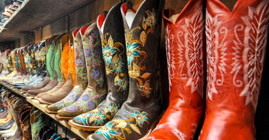 Shelves of colorful cowgirl boots in various sizes and designs line wood-paneled walls in a rustic display.